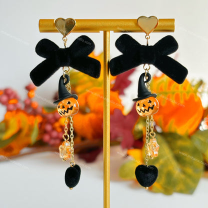 Halloween-themed earrings with jack-o'-lanterns and black bows on a gold stand.