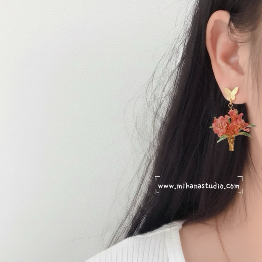 Floral earring worn by a person with a plain background