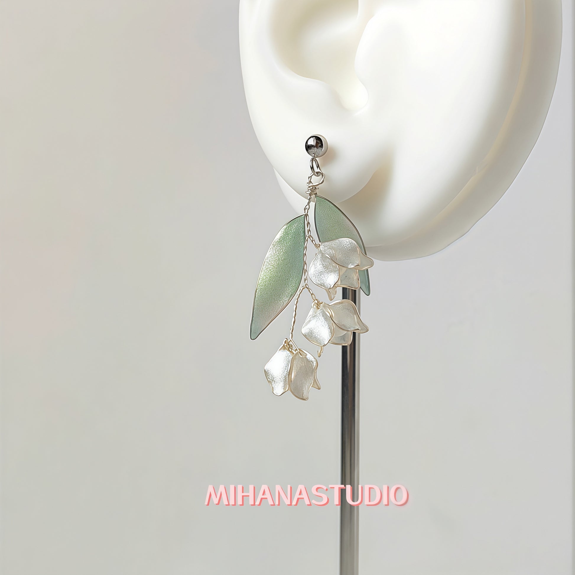 Earring with leaf and pearl-like droplet design on a white ear model, branded 'MIHANASTUDIO'.