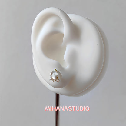 Floral white lily of the valley earring on a mannequin ear with 'MIHANASTUDIO' branding.