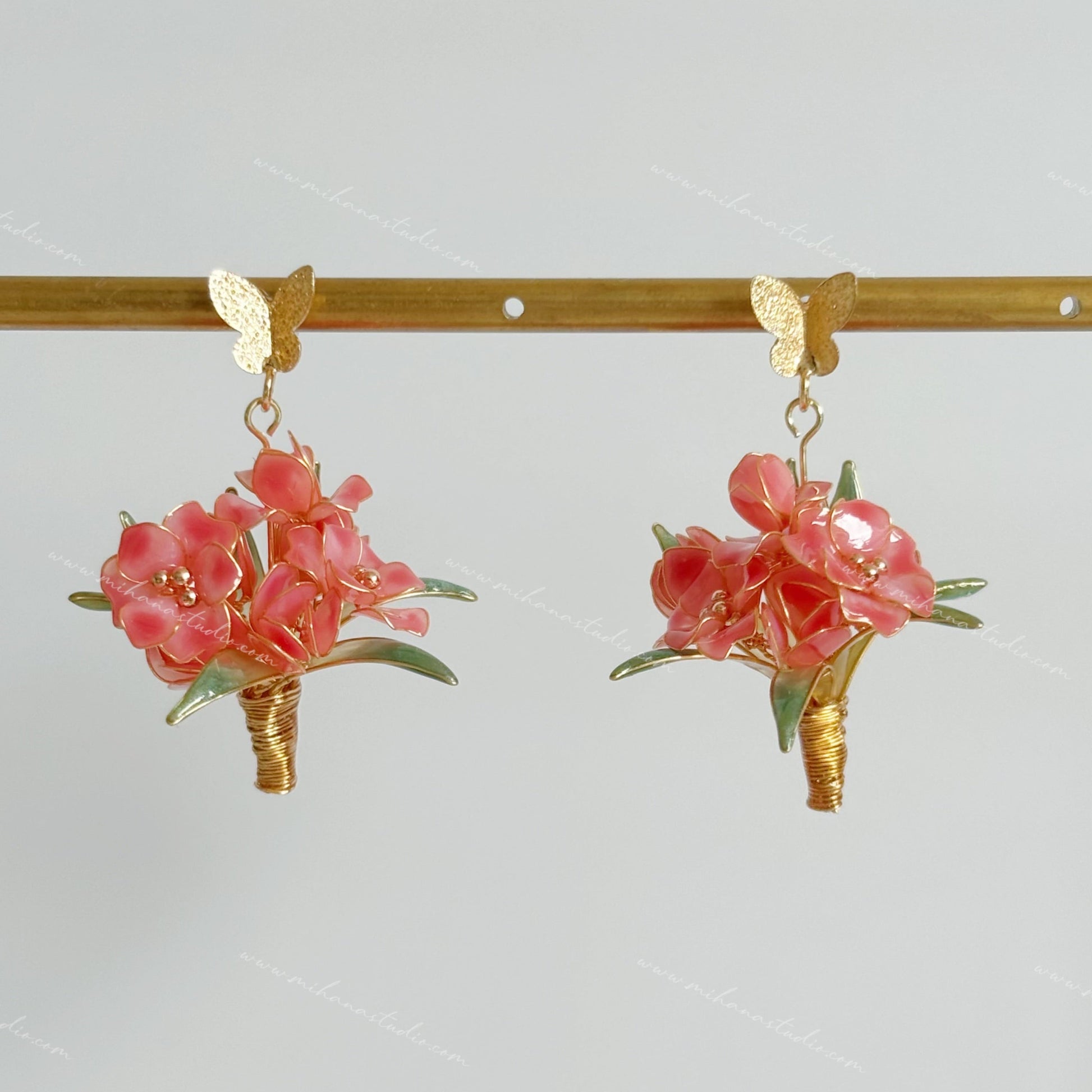 Floral earrings with pink flowers and gold accents on a white background