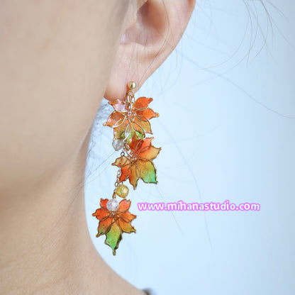 Colorful leaf-shaped earrings worn by a person, with a light background and visible brand 'mihanastudio.com'.