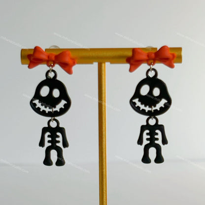 Black skeleton figure earrings with orange bows on a white background