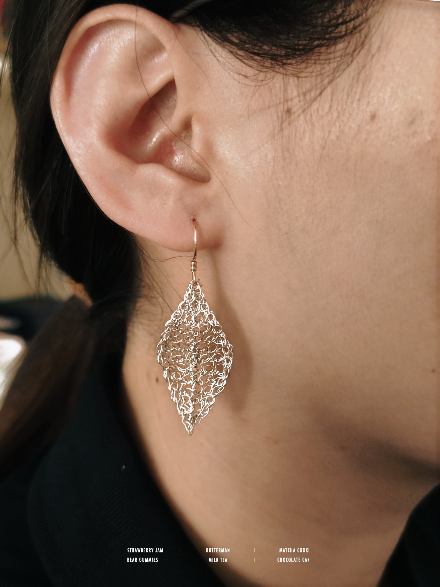 Close-up of a person wearing a silver leaf-shaped earring.