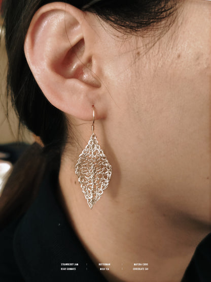Close-up of a person wearing a silver leaf-shaped earring.