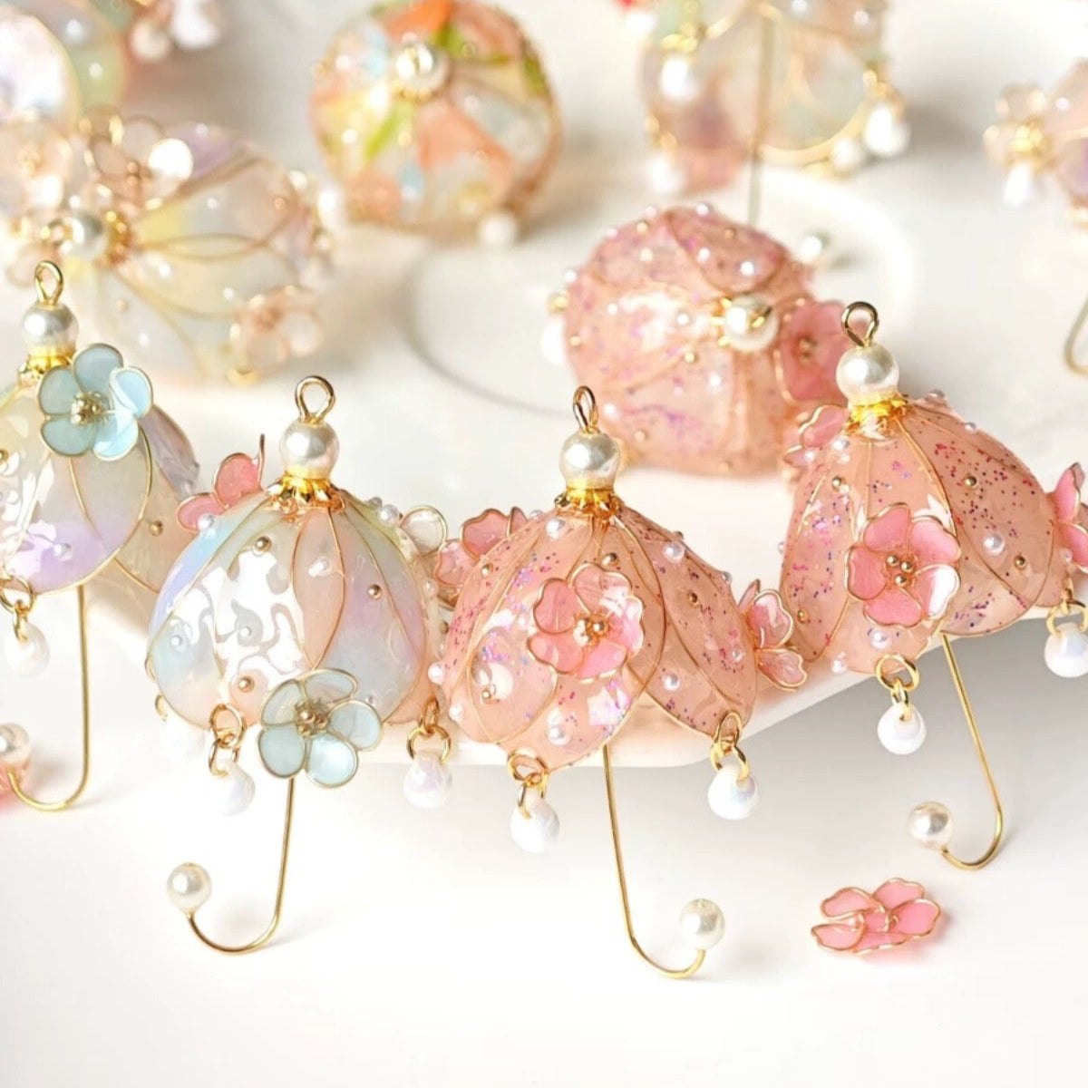 A pair of gold vermeil floral umbrella earrings with multicolored dangles designed to resemble flowers and fruit, displayed on a surface.
