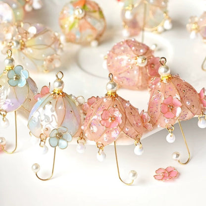 A pair of gold vermeil floral umbrella earrings with multicolored dangles designed to resemble flowers and fruit, displayed on a surface.