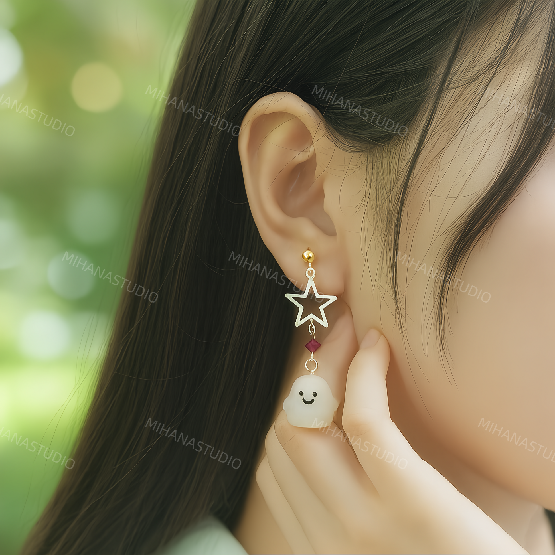 Star-shaped earring with a small face charm worn by a person against a blurred green background