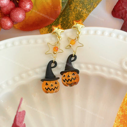 Pumpkin earrings on a white plate with autumn decorations.